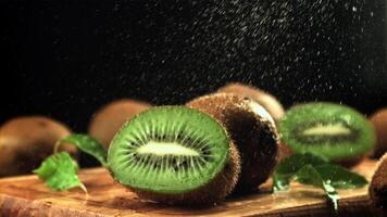 spatten van water vallen Aan de gesneden kiwi. Aan een zwart achtergrond.gefilmd is langzaam beweging 1000 kaders per seconde. hoog kwaliteit full HD beeldmateriaal video