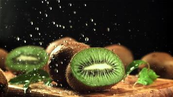 spatten van water vallen Aan de gesneden kiwi. Aan een zwart achtergrond.gefilmd is langzaam beweging 1000 kaders per seconde. hoog kwaliteit full HD beeldmateriaal video