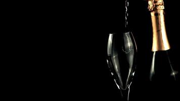 A jet of champagne falls into a glass of splashes and foam. On a black background. Filmed is slow motion 1000 frames per second. High quality FullHD footage video