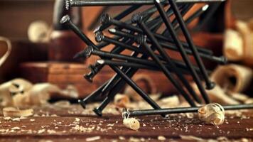 A bunch of nails fall on the table. On a wooden background. Filmed is slow motion 1000 frames per second. video