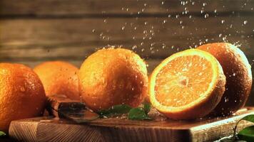 gouttes de l'eau tomber sur le des oranges. sur une en bois Contexte. filmé est lent mouvement 1000 cadres par seconde.haute qualité Full HD métrage video