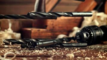 Drill bits fall on a table of sawdust. On a wooden background.Filmed is slow motion 1000 frames per second. High quality FullHD footage video