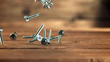 Screws fall on the table. On a wooden background. Filmed is slow motion 1000 frames per second. High quality FullHD footage video