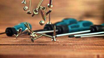 Self-tapping screws fall on a wooden table. On a wooden background. Filmed is slow motion 1000 frames per second. video