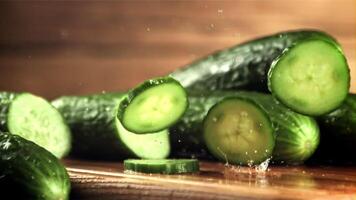 Chopped fresh cucumber falls on the table. On a wooden background.Filmed is slow motion 1000 frames per second. High quality FullHD footage video