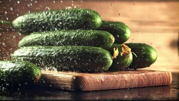 Drops of water fall on the cucumbers on the cutting board. On a wooden background. Filmed is slow motion 1000 frames per second. video