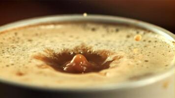 une laissez tomber de mousse chutes dans une tasse de café. macro Contexte. filmé est lent mouvement 1000 cadres par deuxième. video