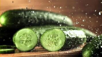 Drops of water with splashes fall on pieces of fresh cucumber. On a wooden background. Filmed is slow motion 1000 frames per second. video