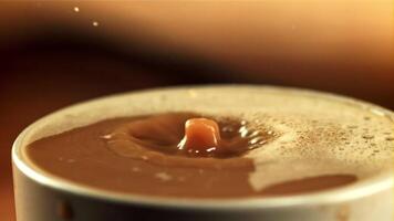 A drop falls into a cup of coffee with milk with splashes. On a wooden background. Filmed is slow motion 1000 fps. video