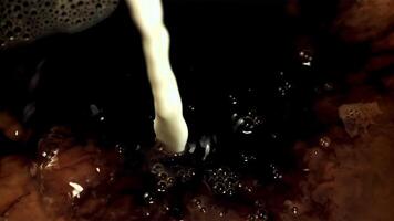 Milk with air bubbles is poured into black coffee. Macro background. Filmed is slow motion 1000 frames per second. High quality FullHD footage video