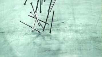 A bunch of nails fall on the table. On a gray background. Filmed is slow motion 1000 fps. video