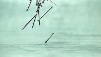 The nails slowly fall on the table. On a gray background. Filmed is slow motion 1000 fps. video