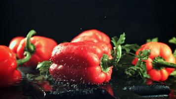 Sweet peppers fall on a cutting board with splashes of water. On a black background. Filmed is slow motion 1000 fps. video