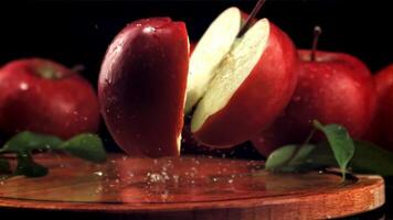 The red apple falls on the cutting board and splits into halves. On a black background.Filmed is slow motion 1000 fps. video