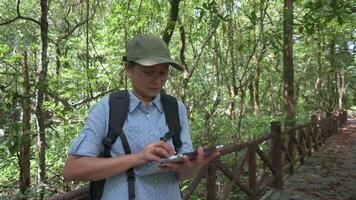 asiatisk kvinna botaniker arbetssätt på digital läsplatta medan utforska och forska de ekosystem av mangrove skog under sommar. utomhus- natur ekologi. miljö- bevarande. video