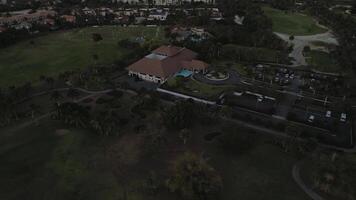 Aerial view of golf club grounds at twilight. Golf course, central structure alongside parking area, surrounded by trees and pathways. Cocotal golf, Dominican, Punta Cana video