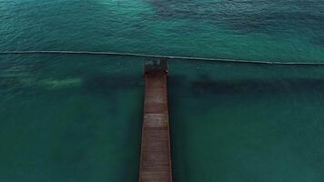 cinematográfico aéreo ver capturar muelle con Kiosko a crepúsculo, conjunto en contra fondo de vibrante turquesa Oceano aguas adecuado para agregando texto. impresionante punta cana video