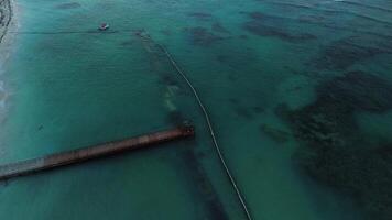 Aerial cinematic perspective capturing a pier featuring a gazebo during twilight, set against the backdrop of vibrant turquoise ocean waters. Suitable for adding text. Impressive Punta Cana video