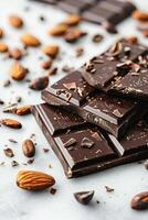 Chocolate bar with cacao beans and almonds scattered around it photo