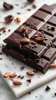 Chocolate bar with cacao beans and almonds scattered around it photo