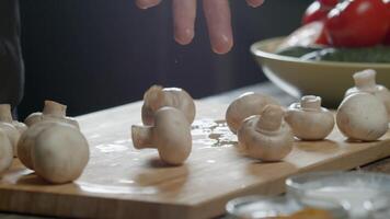 champignons vallen op de tafel van de chef-kok hand- in de keuken van een upscale restaurant, tegen een donker achtergrond. dichtbij omhoog. langzaam beweging. video