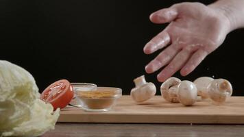 Mens gooit sommige champignons op een houten snijdend bord, en ze stuiteren mooi Aan het. dichtbij omhoog. langzaam beweging. video