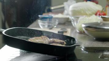 cook is frying chicken in a pan with hot oil. As the meat cooks, splashes of oil fly out in all directions and stain the stove. Close up. Slow motion. video