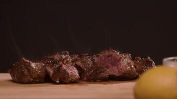 juicy, freshly cut piece of beef rests on a wooden cutting board, emitting an appetizing aroma. background is dark. Close up. Slow motion. video