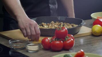 Chicken with vegetables is cooked in a pan with curry seasoning and dried herbs on the stove, a traditional Indian dish. Close up. Slow motion. video