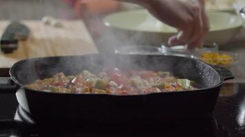 Nahansicht von gedämpft Gemüse - - Tomaten und Zucchini - - bestreut mit getrocknet Kreuzkümmel durch ein erfahren Koch im ein Restaurant. schließen hoch. schleppend Bewegung. video