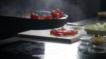 chef bereidt zich voor een heerlijk groente stoofpot in een pan gebruik makend van vers rood klok paprika's. hij mengsels hen in de pan gebruik makend van de roerbak techniek. dichtbij omhoog. langzaam beweging. video