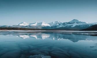 A distant view of snow-capped mountains reflected in the frozen surface of a lake photo