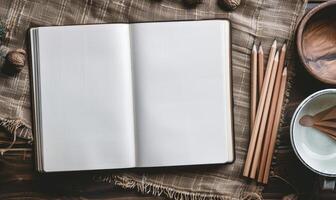 A sketchbook open to a blank page with graphite pencils beside it photo