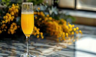 Cocktail in a glass goblet with mimosa branches in the background photo