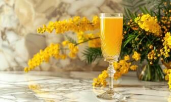 Cocktail in a glass goblet with mimosa branches in the background photo