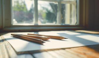 Graphite pencils and white paper illuminated by natural through a window photo