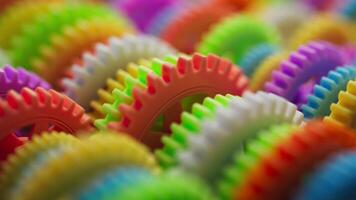 Looping 3D animation of a group of multi-colored plastic toy gears. Close-up. Defocus video