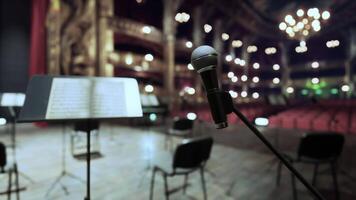 A microphone and a sheet music stand in front of a stage video