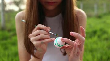 Girls' hands paint Easter eggs with paints of different colors in the open air. Watercolor painting on eggs. Close-up of hands video