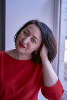 portrait of a brunette with a bob haircut in a red sweater and a leather mini skirt in the office photo