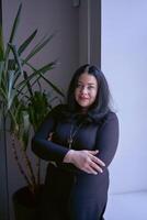 portrait of a medium size woman with black hair in a black dress in an office photo