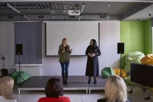 two women give a speech on stage photo