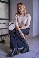 blonde woman in a light sweater and wide pants in the office photo