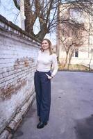 a beautiful middle age woman in a sweater and  chic wide leg pants  outside on a spring day photo