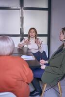 three women, including a person with a disability, discuss the company's strategy at a meeting in the office photo