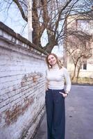 a beautiful middle age woman in a sweater and  chic wide leg pants  outside on a spring day photo