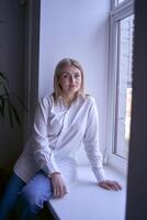 portrait of a blonde woman in jeans and a white shirt in the office photo