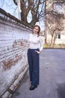 a beautiful middle age woman in a sweater and  chic wide leg pants  outside on a spring day photo