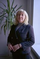 portrait of a blonde middle age woman in a business suit in the office photo