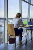 middle age woman working on a laptop in a coworking space with panoramic windows and a view of the city from above, laptop with a green screen, Chroma key photo